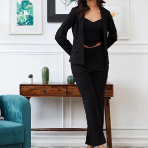 black three-piece suit featuring a tailored blazer, a trendy crop top, and straight-fit pants, paired with black heels and a handbag in a modern indoor setting