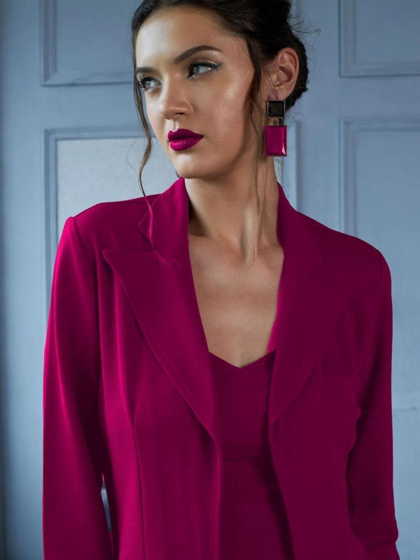 black three-piece suit featuring a tailored blazer, a trendy crop top, and straight-fit pants, paired with black heels and a handbag in a modern indoor setting