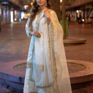 White embroidered lehenga set with golden embellishments, paired with a matching dupatta, displayed on a mannequin in a stylish setting.