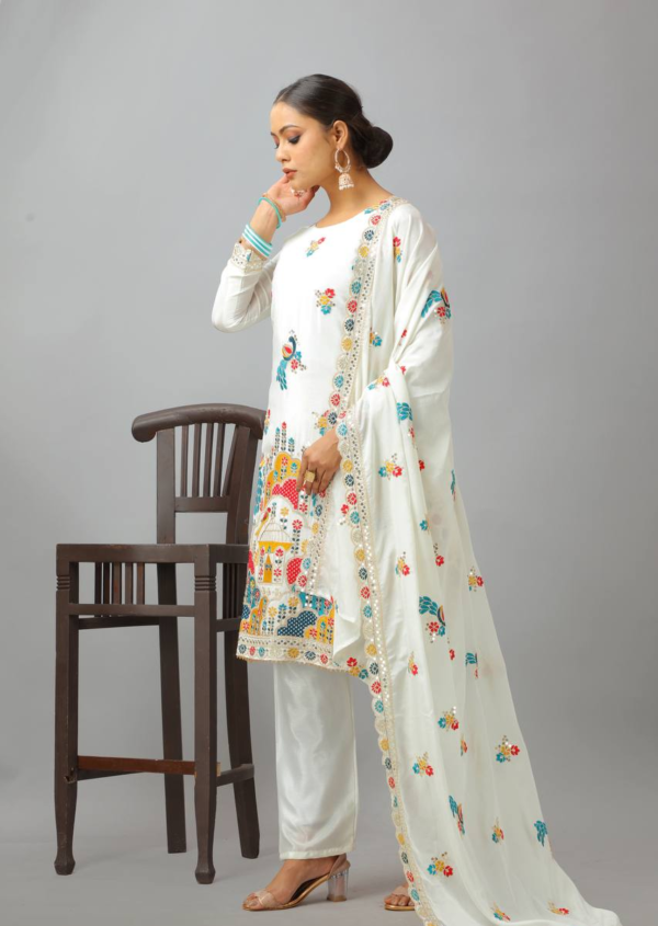 Woman wearing a white embroidered kameez set with a matching dupatta and fully stitched bottom, featuring intricate multicolor detailing.