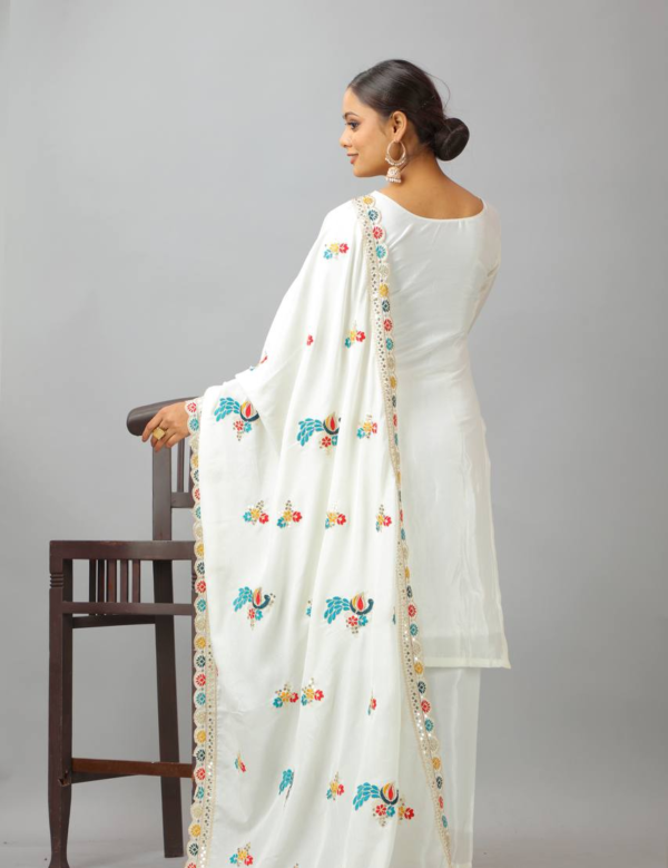 Woman wearing a white embroidered kameez set with a matching dupatta and fully stitched bottom, featuring intricate multicolor detailing.